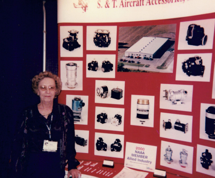 Mary Turner standing by S & T Aircraft's booth at the NAAA convention