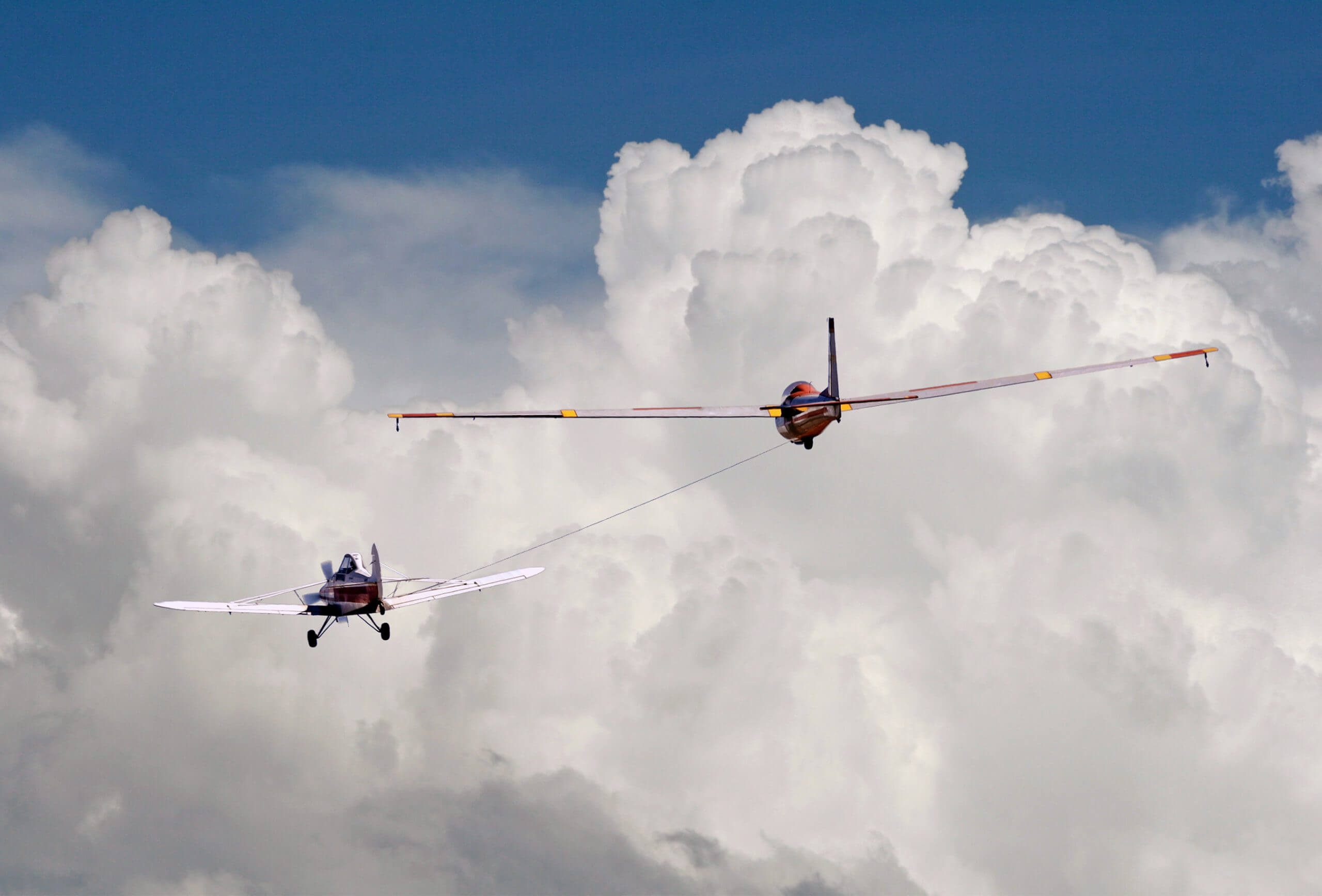 Glider being pulled by a tow plane into the sky.